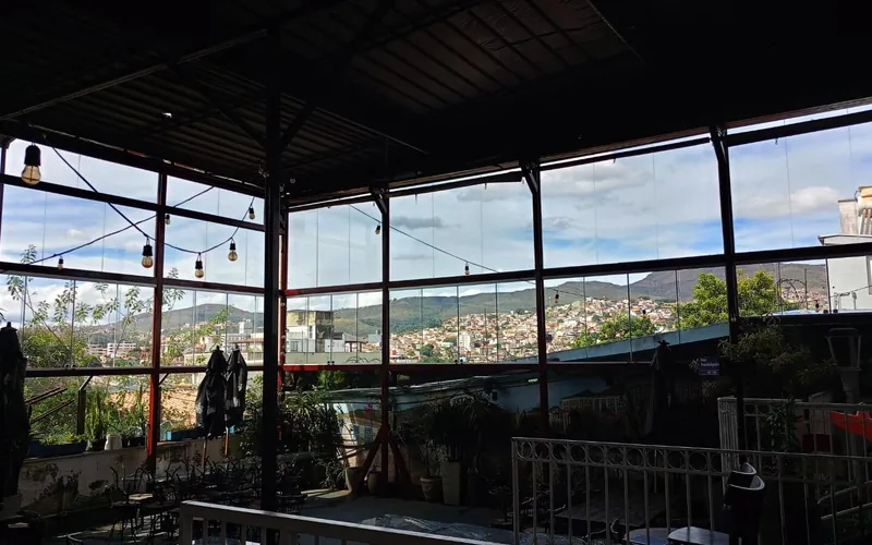 Área coberta fechada com painéis de vidro e vista para a cidade